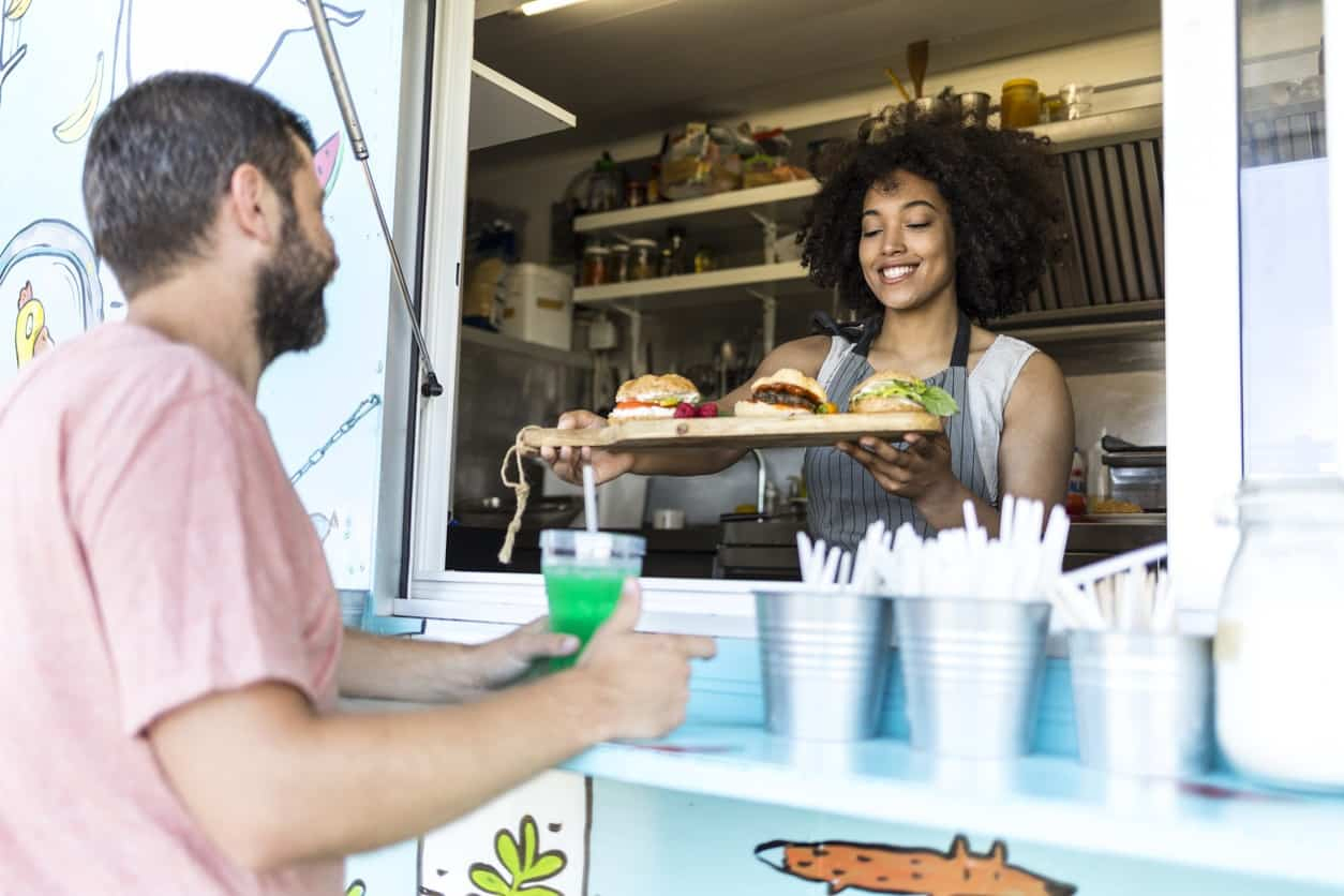 Woman serving man food from food truck